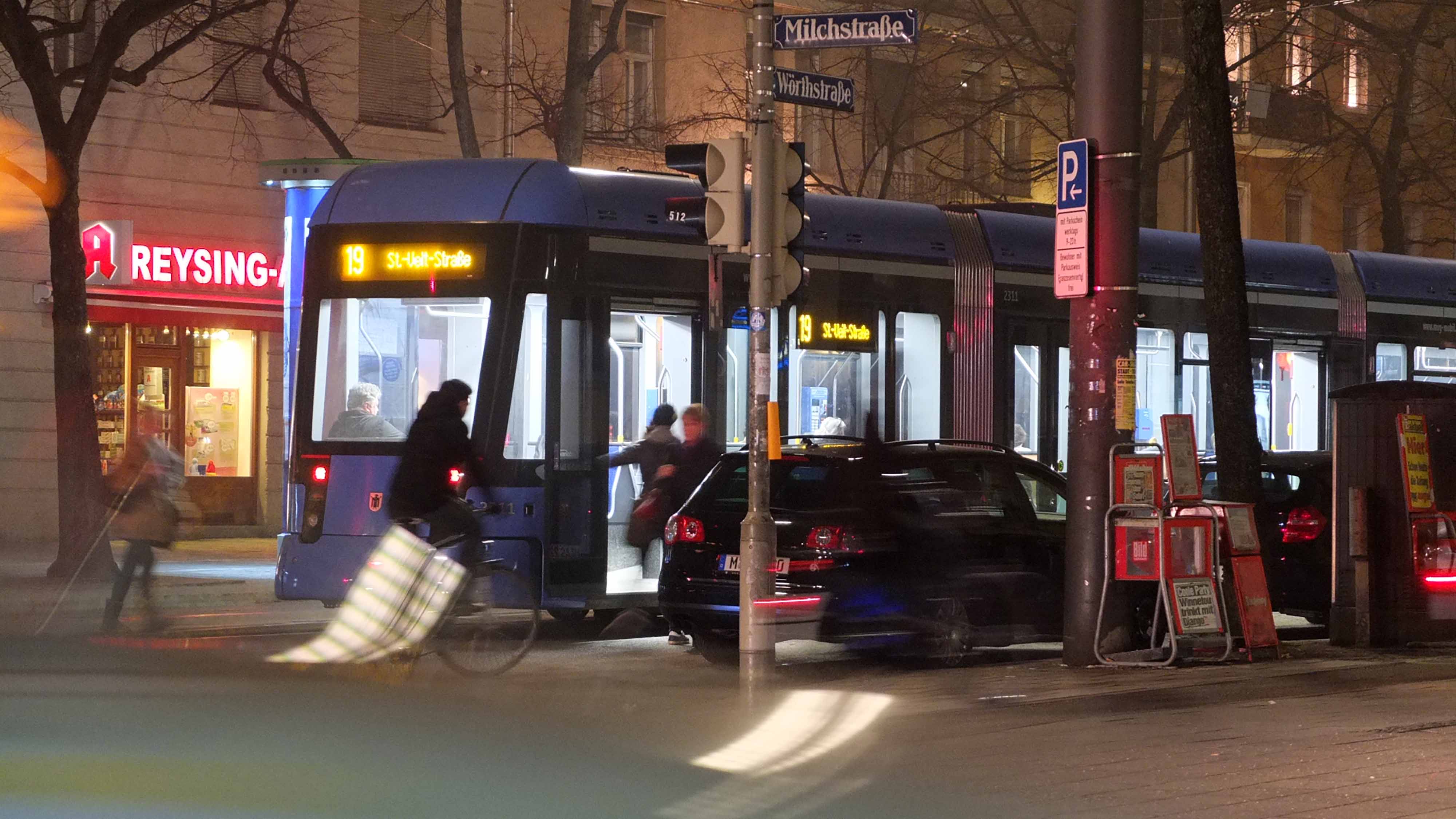 Das Neonlicht der Straßenbahn ist kälter und grünlicher als die wärmere Ladenbeleuchtung